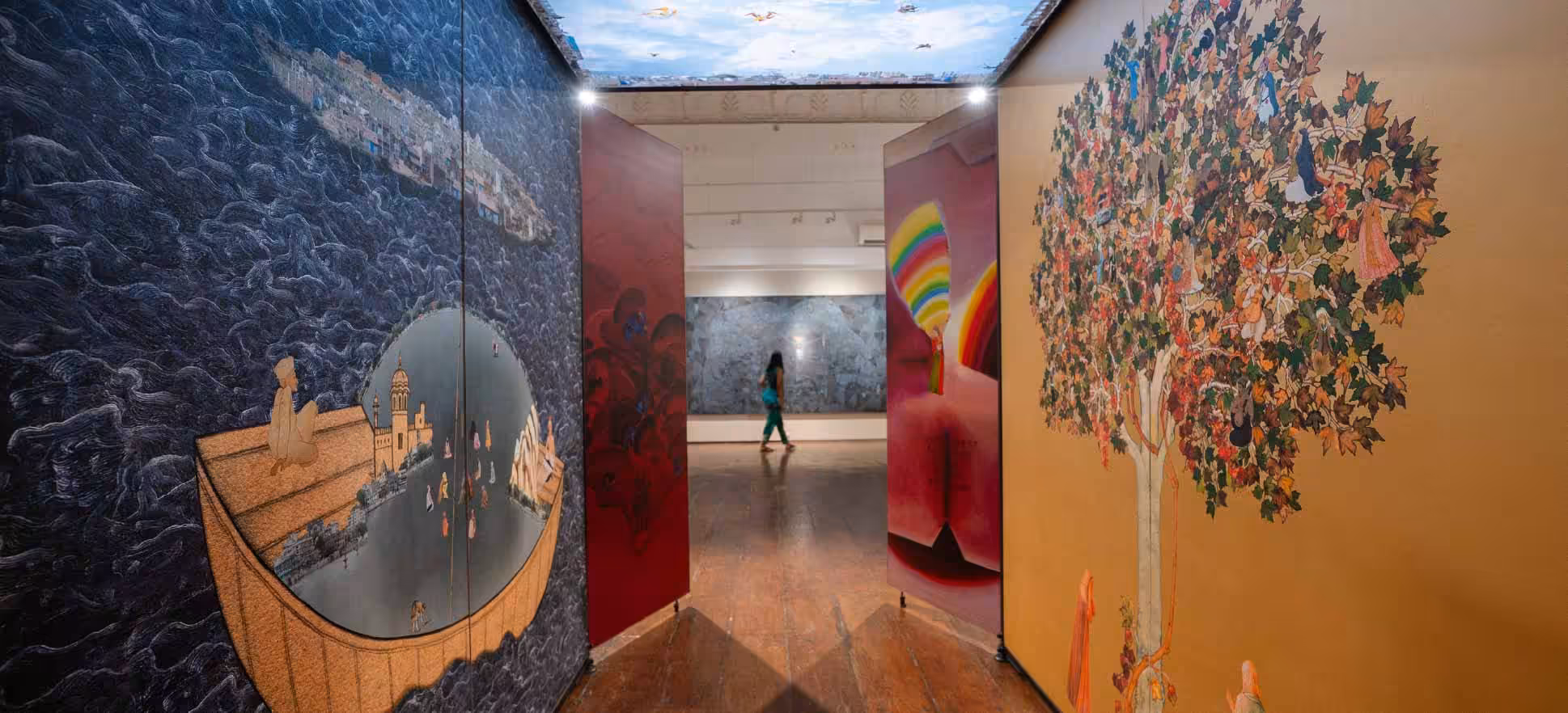 Exhibition banner for 'of worlds within worlds', featuring artworks by Gulammohammed Sheikh at the Kochi-Muziris Biennale, presented by KNMA